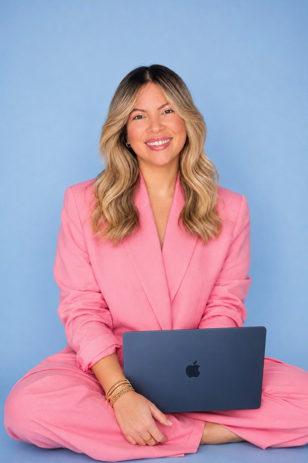 Yarelis Marín, sonriendo, con traje rosa y una laptop
